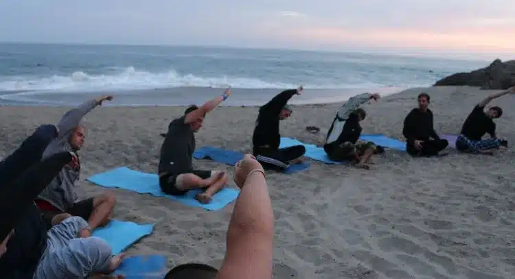 A group of people practicing yoga outdoors in a serene natural setting. - Holistic Drug Rehab